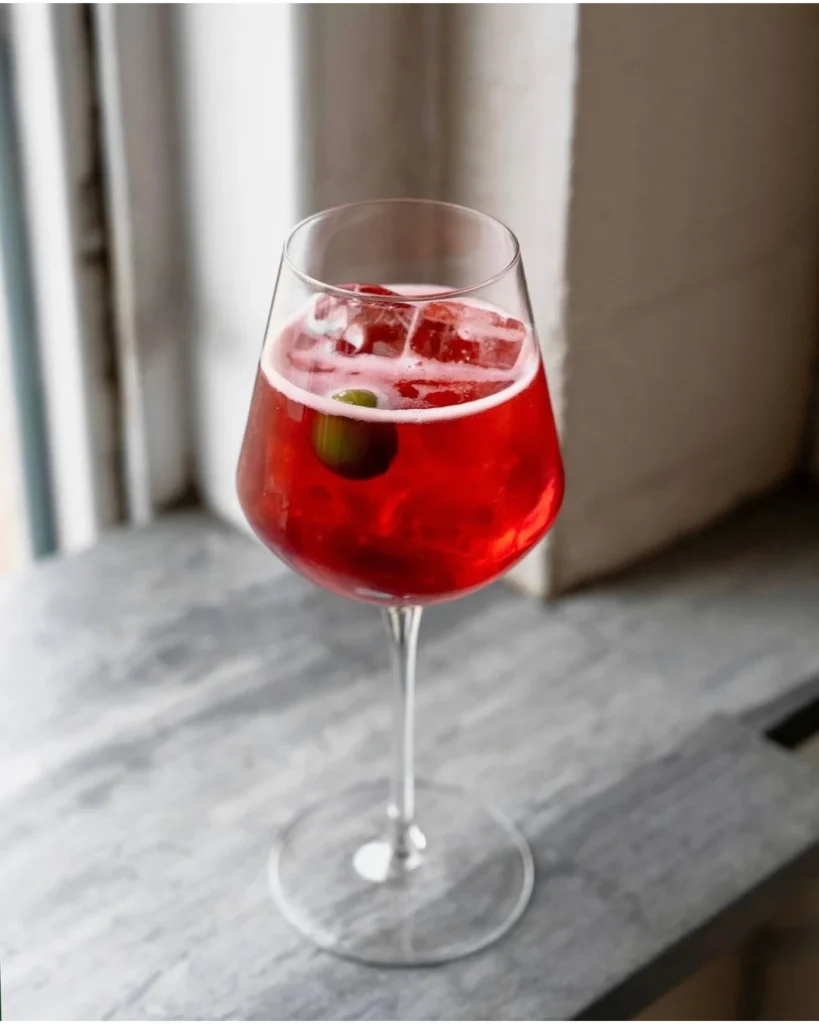 Spritz al Select en Venecia: el aperitivo botánico de color rojo rubí con aceituna verde, diferenciado del spritz común por su amargor complejo y origen histórico en 1920.