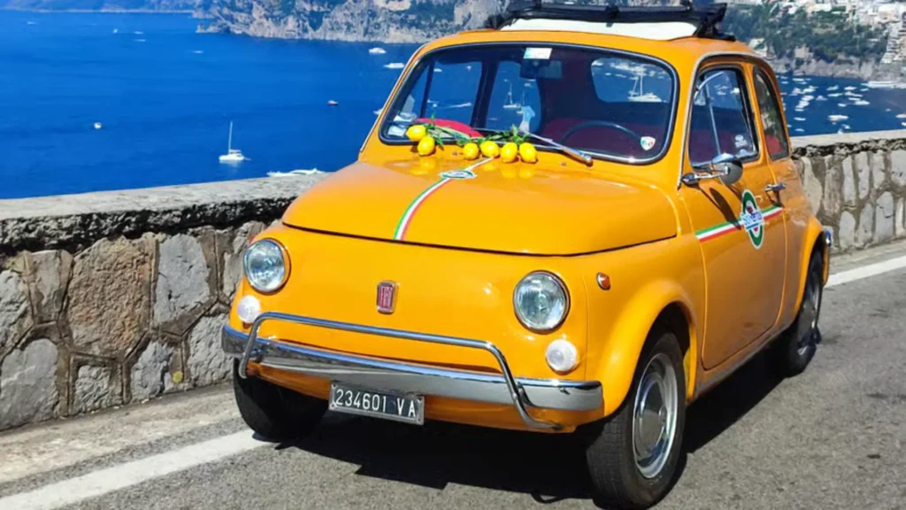 Fiat 500 clásico en la Costa Amalfitana, Italia; símbolo del estilo de vida mediterráneo y el lujo vintage.