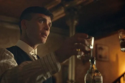 Cillian Murphy en el papel de Thomas Shelby bebiendo whisky en una escena icónica de la serie Peaky Blinders.