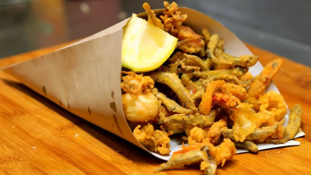 Tradicional cuoppo di mare en Salerno: un cono de papel lleno de pescados pequeños, calamares y gambas fritas al estilo artesanal frente al puerto.