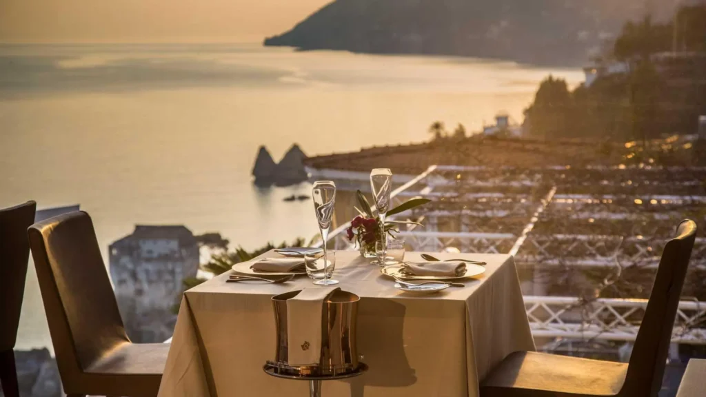 Terraza panorámica del restaurante Re Maurì con estrella Michelin, mostrando mesas de gala frente a la inmensidad del Golfo de Salerno y los acantilados de la Costa Amalfitana.