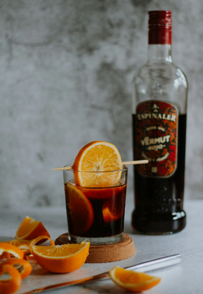 Vermut rojo con rodajas de naranja alrededor.