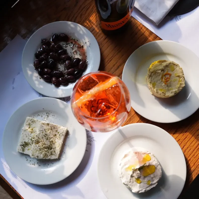 Aperitivo italiano con spritz y cocina griega en Mythos Estiatorio en Ciudad de México, con gyros, tapas mediterráneas y prosecco servido en mesa