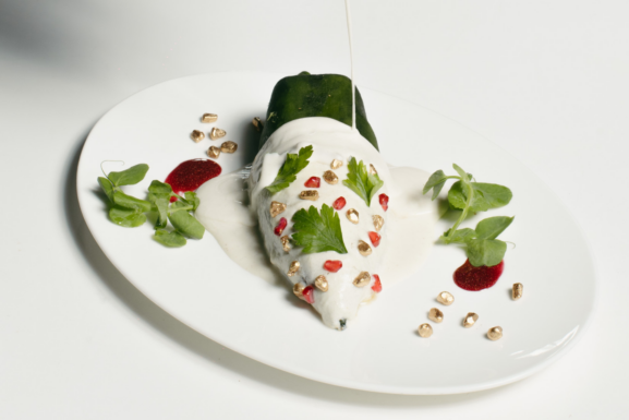 Chile en Nogada de Fónico, restaurante en CDMX, servido con nogada de nuez y granada.