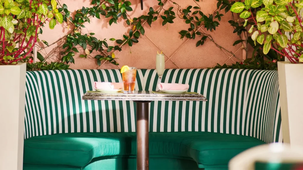 Sillón exterior a rayas con limonadas frente a una pared rosa en The Beverly Hills Hotel.