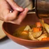 Una mano sirve un platillo en la cocina de Bribona, restaurante de cocina mexicana contemporánea en San Miguel Chapultepec, CDMX.