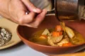 Una mano sirve un platillo en la cocina de Bribona, restaurante de cocina mexicana contemporánea en San Miguel Chapultepec, CDMX.