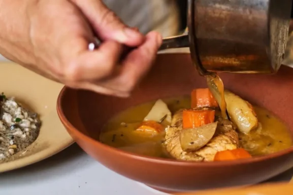 Una mano sirve un platillo en la cocina de Bribona, restaurante de cocina mexicana contemporánea en San Miguel Chapultepec, CDMX.