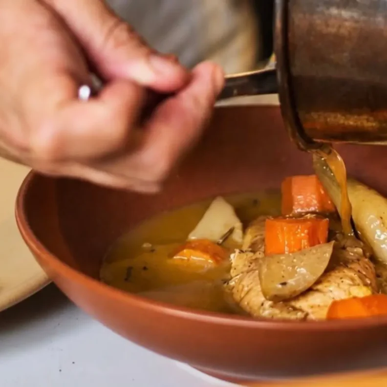 Una mano sirve un platillo en la cocina de Bribona, restaurante de cocina mexicana contemporánea en San Miguel Chapultepec, CDMX.